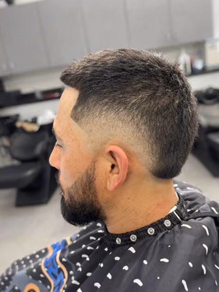 Burst Fade Mohawk & Textured Crop with Beard - Curved burst fade leaving density down the nape, blunt forward crop fringe, and tailored beard connection.